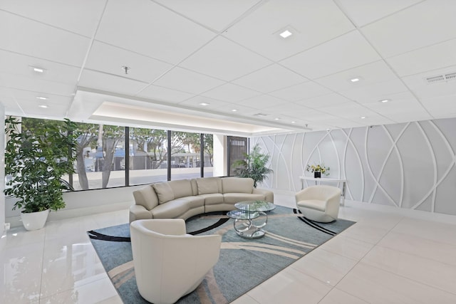 living room with a drop ceiling and tile patterned floors