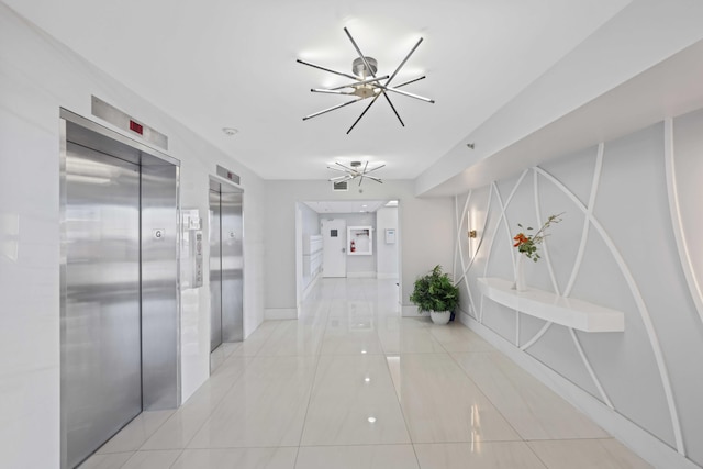 corridor with a notable chandelier, light tile patterned floors, and elevator