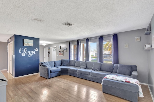 living room with a textured ceiling and light wood-type flooring