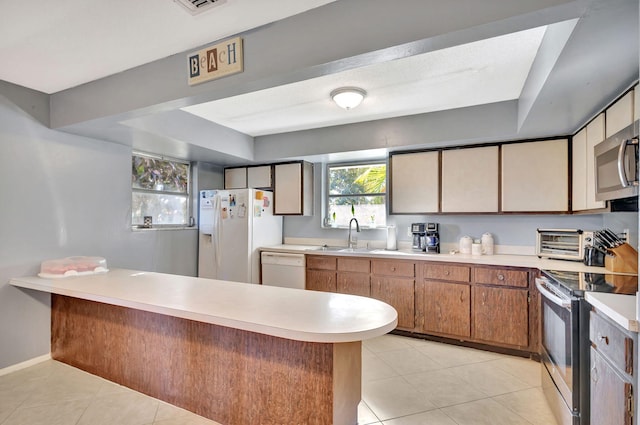 kitchen featuring sink, light tile patterned floors, stainless steel appliances, and kitchen peninsula