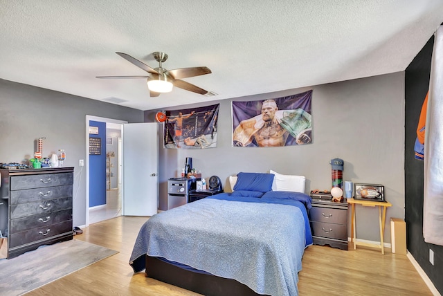 bedroom with a textured ceiling, light hardwood / wood-style flooring, and ceiling fan