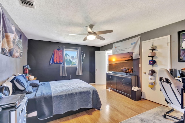 bedroom with ceiling fan, a textured ceiling, and light hardwood / wood-style floors