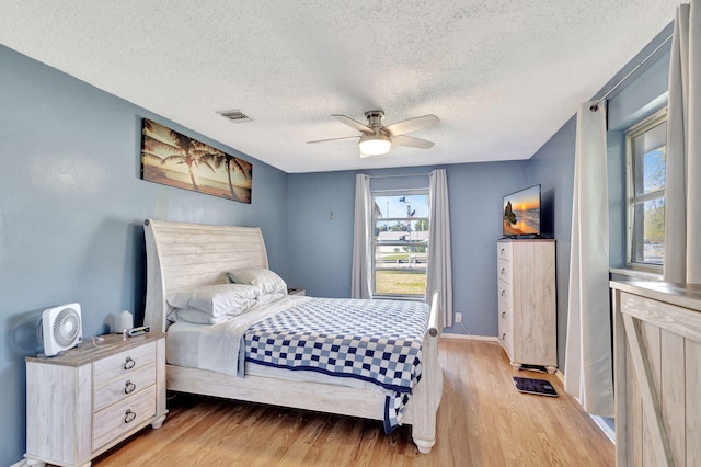 bedroom with ceiling fan, a textured ceiling, and light wood-type flooring