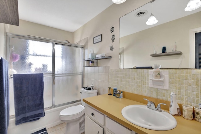 full bathroom featuring toilet, shower / bath combination with glass door, tile walls, vanity, and tile patterned flooring