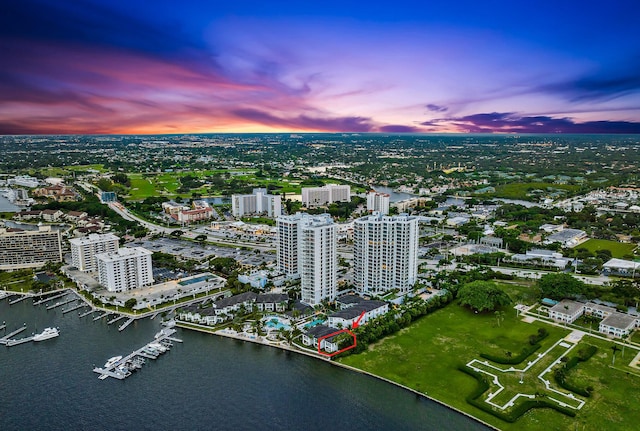 aerial view at dusk featuring a water view and a view of city