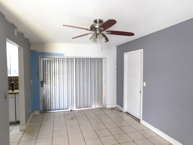 tiled empty room featuring ceiling fan and a textured ceiling