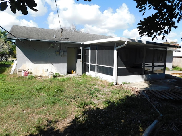 rear view of house featuring a sunroom and a yard