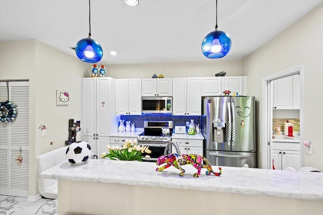 kitchen featuring stainless steel appliances, pendant lighting, white cabinets, and backsplash