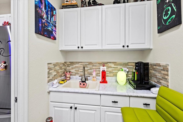 kitchen with sink, white cabinets, and backsplash