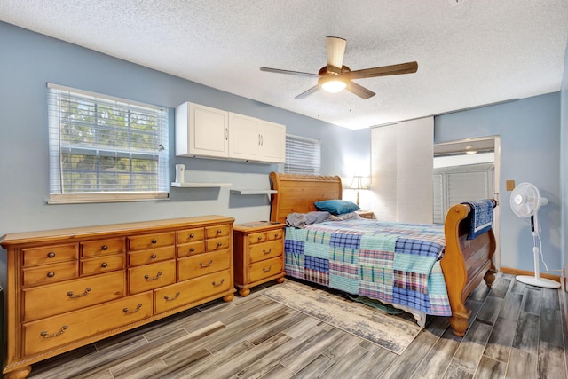 bedroom with ceiling fan, hardwood / wood-style floors, and a textured ceiling