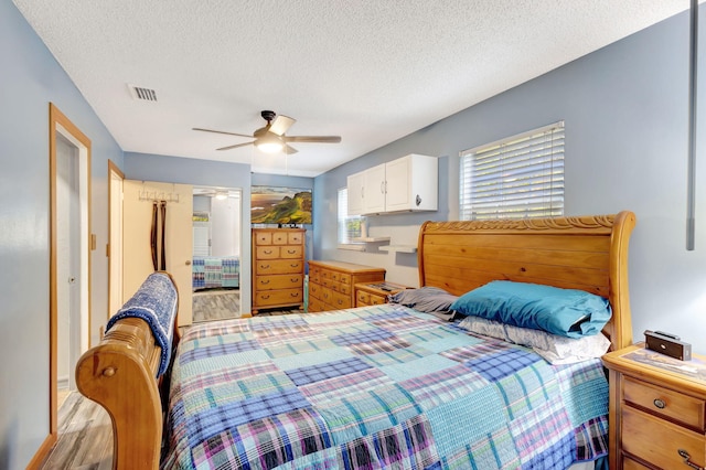 bedroom with ceiling fan, a textured ceiling, and light wood-type flooring