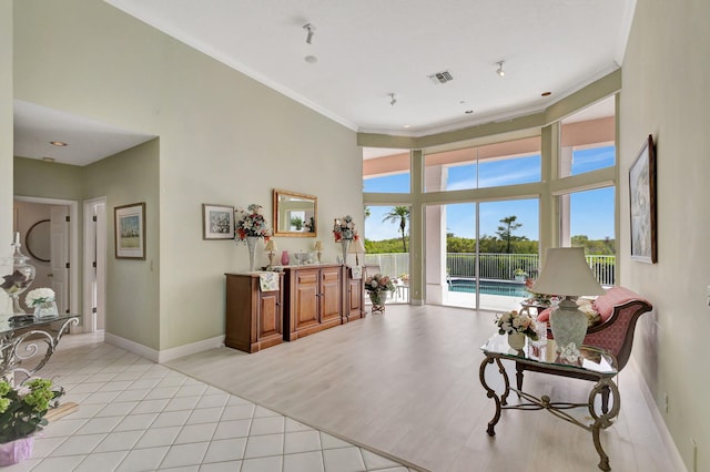 living area featuring light tile patterned flooring, ornamental molding, and a high ceiling