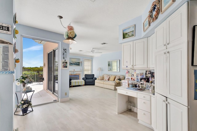 kitchen with white cabinetry, a textured ceiling, ceiling fan, and light hardwood / wood-style flooring