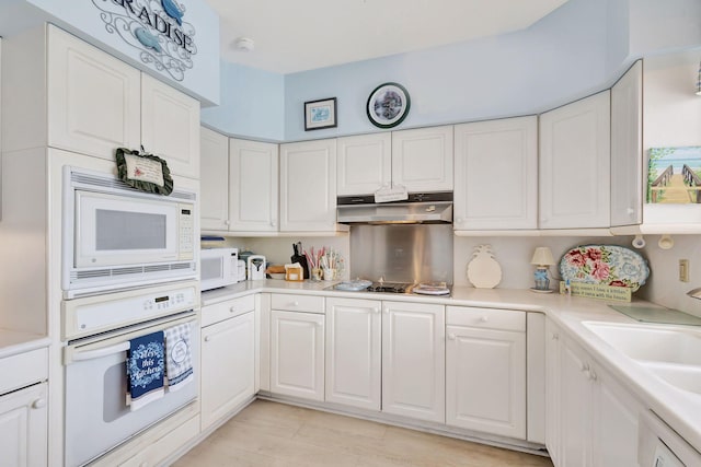 kitchen with sink, white appliances, and white cabinets