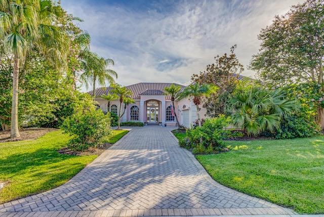 mediterranean / spanish-style house with a garage and a front lawn