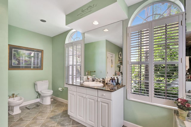 bathroom with a bidet, vanity, toilet, and tile patterned flooring