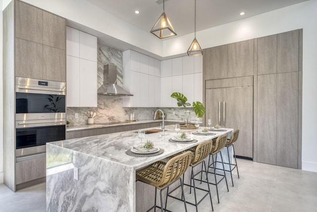 kitchen with double oven, white cabinets, a kitchen bar, hanging light fixtures, and a spacious island