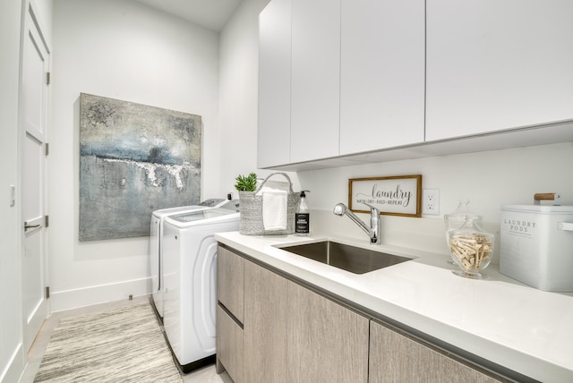 washroom with cabinets, sink, and independent washer and dryer