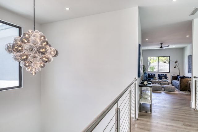 corridor featuring an inviting chandelier and light hardwood / wood-style flooring