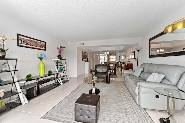 living area with tile patterned flooring, visible vents, a chandelier, and a textured ceiling