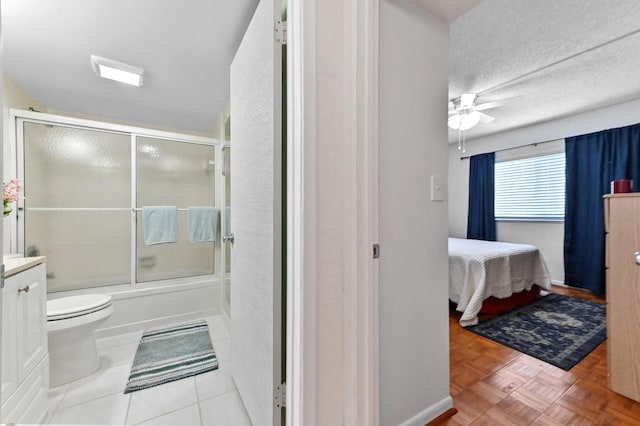 full bath with toilet, combined bath / shower with glass door, ceiling fan, vanity, and ensuite bath