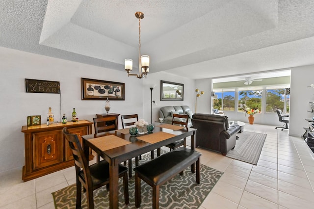 dining room featuring light tile patterned floors, a raised ceiling, a textured ceiling, and ceiling fan with notable chandelier