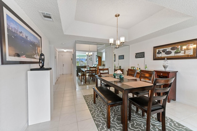 dining space with light tile patterned floors, a tray ceiling, visible vents, and a notable chandelier