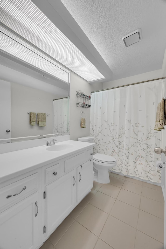 bathroom with vanity, toilet, tile patterned flooring, and a textured ceiling