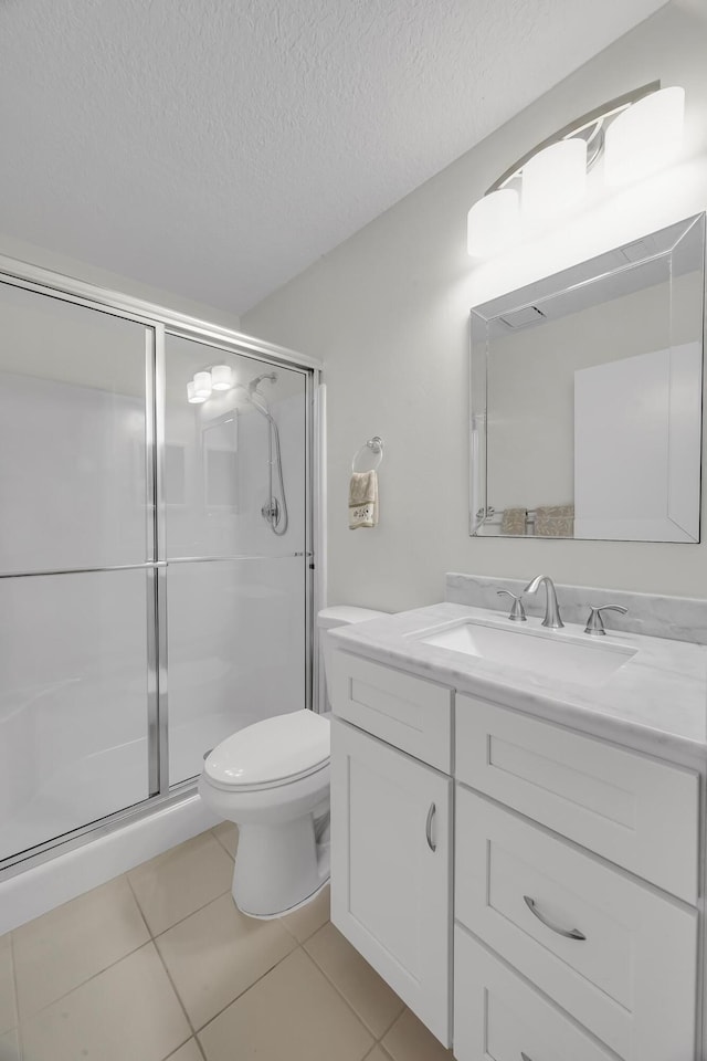 bathroom featuring a shower with door, vanity, a textured ceiling, tile patterned floors, and toilet