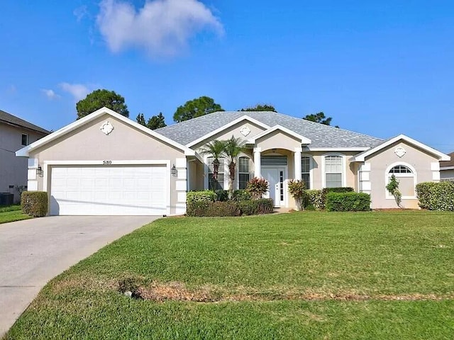 ranch-style home featuring a garage, driveway, a front yard, and stucco siding