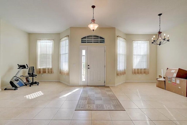 entryway with light tile patterned floors, a chandelier, and baseboards