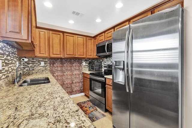 kitchen featuring tasteful backsplash, sink, light tile patterned floors, light stone counters, and stainless steel appliances