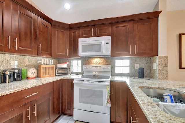 kitchen with white appliances, light stone countertops, and decorative backsplash