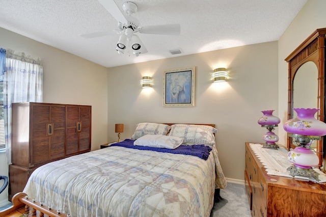 bedroom with light carpet, ceiling fan, and a textured ceiling