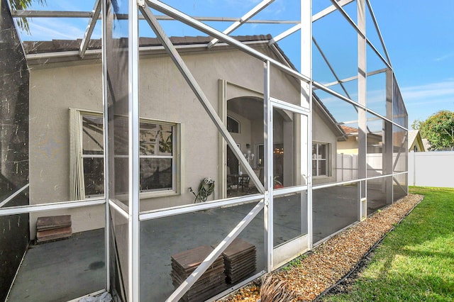 view of side of property with a patio area and glass enclosure