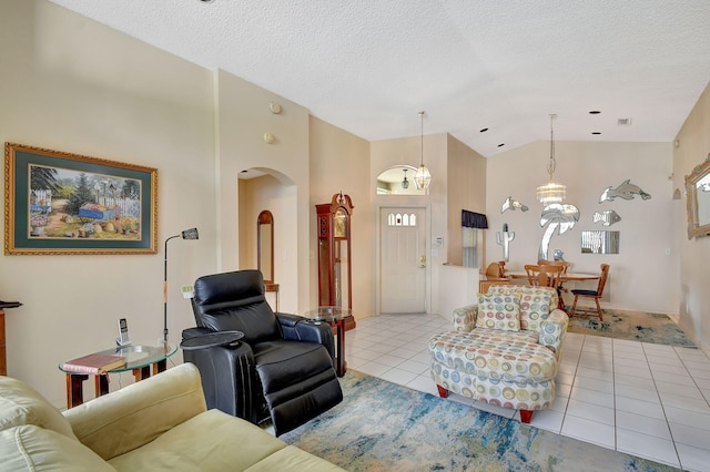 living room with light tile patterned flooring, high vaulted ceiling, an inviting chandelier, and a textured ceiling