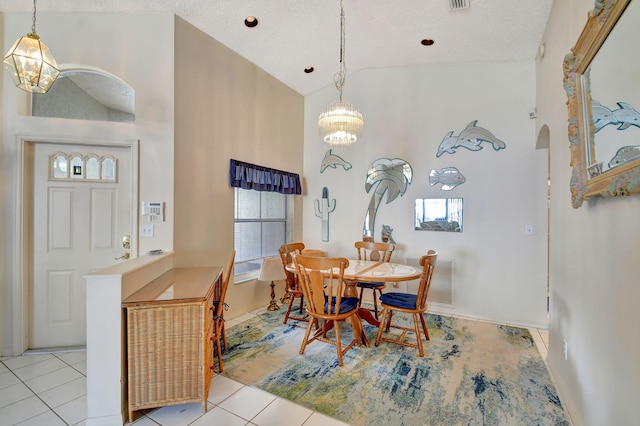 dining space featuring light tile patterned flooring, high vaulted ceiling, a textured ceiling, and an inviting chandelier