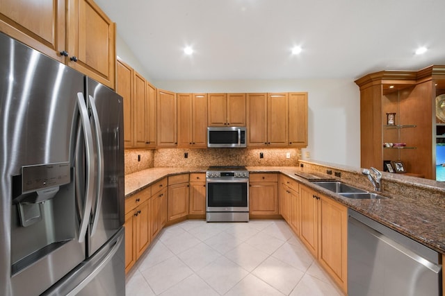 kitchen with dark stone countertops, sink, decorative backsplash, and appliances with stainless steel finishes