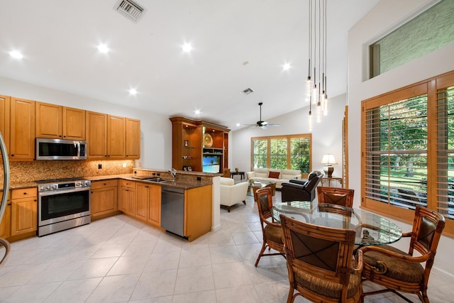 kitchen with sink, dark stone counters, kitchen peninsula, stainless steel appliances, and backsplash