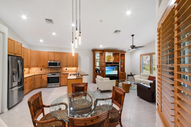 dining room featuring light tile patterned floors, vaulted ceiling, sink, and ceiling fan