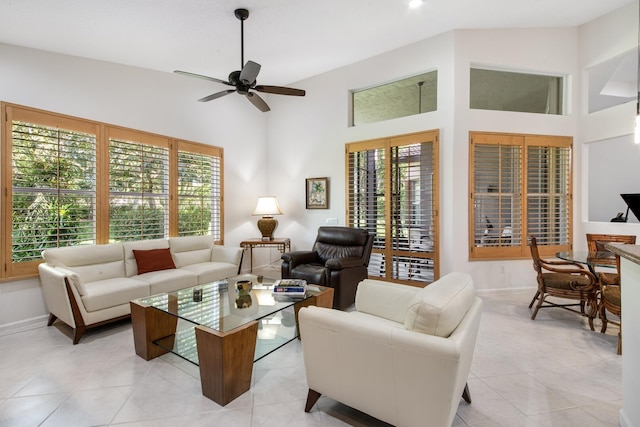 living room with light tile patterned flooring, plenty of natural light, a towering ceiling, and ceiling fan
