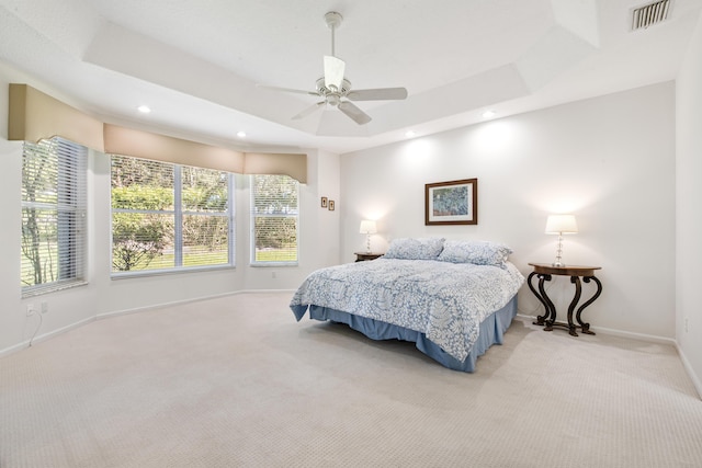 carpeted bedroom with ceiling fan and a tray ceiling
