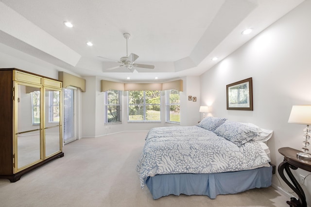 carpeted bedroom with a tray ceiling and ceiling fan