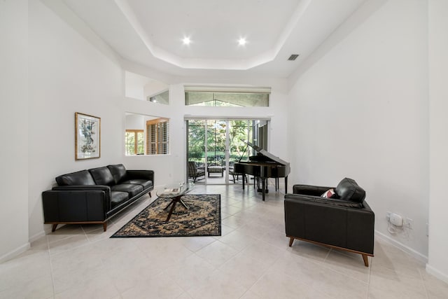 living room with light tile patterned flooring, a raised ceiling, and a high ceiling