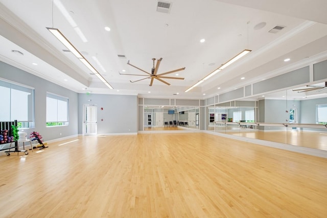 exercise room featuring crown molding, a tray ceiling, light hardwood / wood-style floors, and ceiling fan