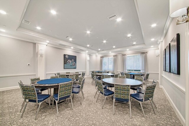 dining area featuring light carpet, crown molding, and a raised ceiling