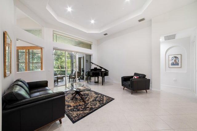 tiled living room featuring a tray ceiling and a high ceiling