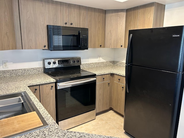 kitchen featuring light tile patterned floors, black appliances, and light stone countertops