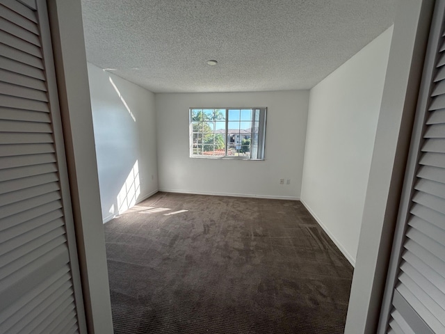 unfurnished room featuring dark carpet and a textured ceiling