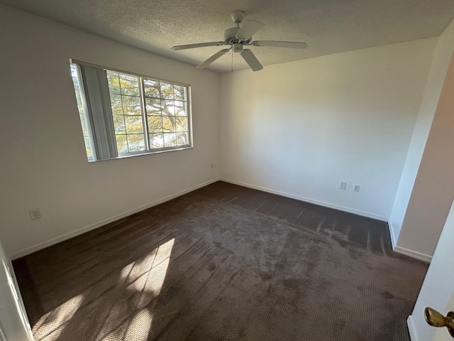 unfurnished room with ceiling fan, dark carpet, and a textured ceiling